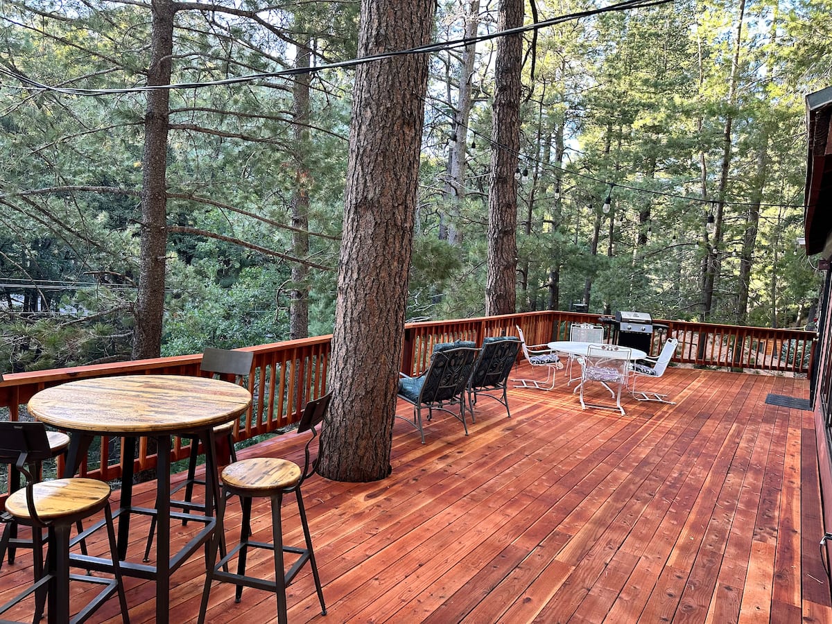 Spacious wood deck with seating and a grill among pine trees